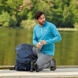 ein mann mit blauem poloshirt macht eine pause bei einer wanderung