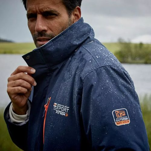 ein mann tragt einen wasserabweisenden blauen windbreaker unter dem regen